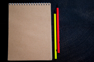 notebook with yellow and orange pencils on a dark background