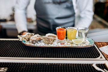 Fresh open oysters with a set of shoot alcoholic cocktails served on table. Seafood delicios