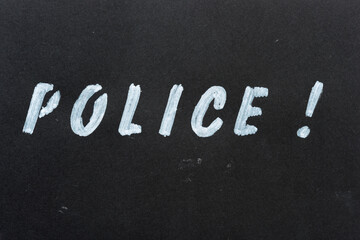 the word "police" stencilled in white marker on black paper background