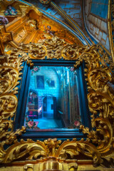 Detail view of the reflection of a mirror with carved wooden forms in the interior chapel of the old religious cathedral of Cuenca, a World Heritage city, Spain.