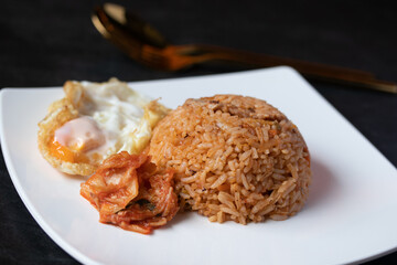 Kimchi lettuce fried rice with fried egg in white plate on black background