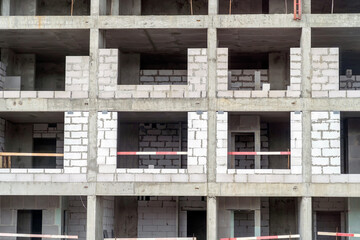 Monolithic concrete building under construction, facade with front view of aerated concrete blocks. View on apartment building floors under construction