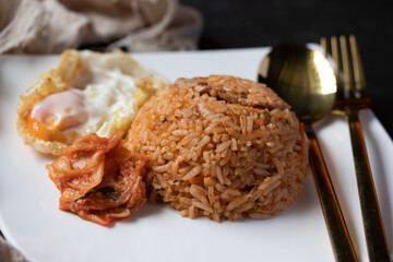 Kimchi lettuce fried rice with fried egg in white plate on black background
