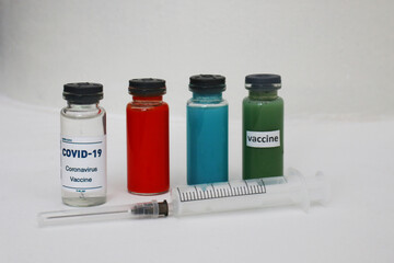 Four ampoules with vaccine and medicines and a syringe on a light background.