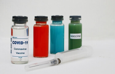 Four ampoules with vaccine and medicines and a syringe on a light background.