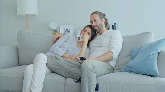 Caucasian loving couple watch movie together in living room at home. 