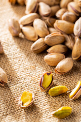 Pistachios nuts on a burlap. Salted, roasted green pistachios on sackcloth background. Healthy snack. Top view