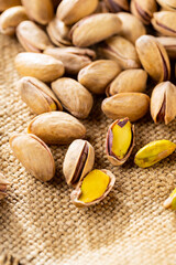 Pistachios nuts on a burlap. Salted, roasted green pistachios on sackcloth background. Healthy snack. Top view