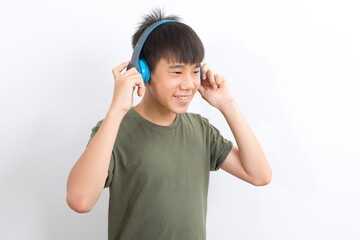 Asian boy with wireless headphones listening to music and dancing on white background.