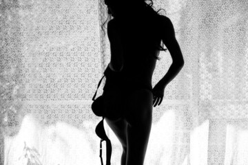 Silhouette rear art nude of fit woman by window