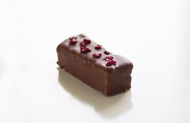 Homemade chocolate bar with dry piece of cherry on top on the white background