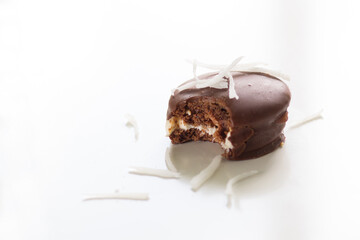 Homemade bitten chocolate pie with coconut chips on top on the white background
