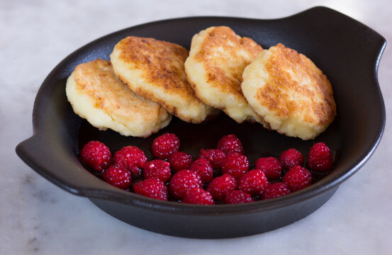 Close Up Fried Homemade Syrniki With Fresh Raspberry On Black Plate On Marble Background