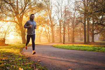 Adult male runner in park at autumn sunrise - obrazy, fototapety, plakaty