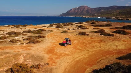 Schilderijen op glas Aerial view of buggy car on the sandy on the sea coast of Cyprus or Greek in summer. Extreme trip off road place. Outdoor adventure for tourists © Maria Sbytova