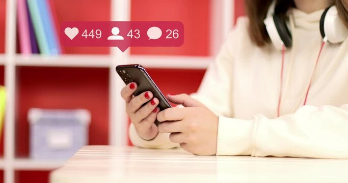 Hand of girl using smartphone in the living room at home, typing message. Animated comments, likes, follower, counter user interface quick increase close up.