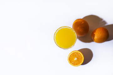 glass with fresh juice and oranges on a light background. Top view, flat lay