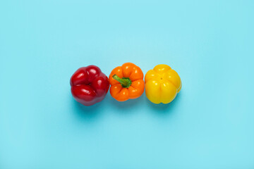 Three fresh bright sweet peppers on a blue background. Top view, flat lay
