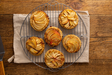 Mini Apple pie tartlets with walnut on wooden table. Delicious dessert for autumn winter dinner.Top view.