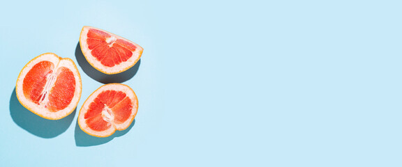 cut halves of grapefruit on a blue background. Top view, flat lay. Banner