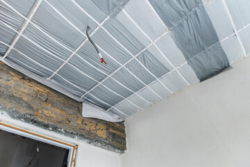 Insulation of the ceiling with mineral wool and covering with heat-saving material. Bottom up view