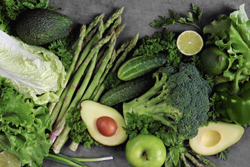 Green healthy vegetables on gray concrete. Green food. The concept of healthy eating. Diet. Asparagus, broccoli, avocado, lime, parsley, basil, apple. Food background. Vegetarian food.
