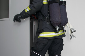 Fototapeta premium a firefighter in protective clothing, with fire-fighting equipment, enters the doorway