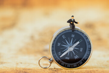 Miniature Business man people office worker sitting on golden compass thinking business plan solve problem using for Accounting Financial Banking business growth development and Commerce Strategy Plan