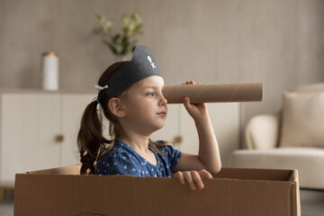 Funny cute kid girl playing pirate at home. Little child in buccaneer black hat sailing in...