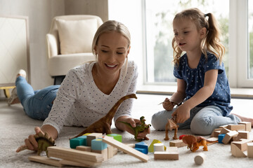 Happy positive mom and kid playing with dinosaurs, talking about extinct animals and paleontology...