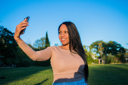 Happy Hispanic Millennial Teenager Checking Social Media With Smartphone . A Young Smiling Latin American Girl Using A Mobile Phone App Playing Games, Shopping Online.