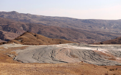 People walk near a mud volcano.