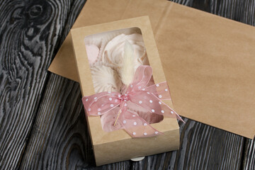 Homemade marshmallows in craft packaging. Zephyr in the form of a rose. Decorated with ribbon and lagurus. Close-up shot.