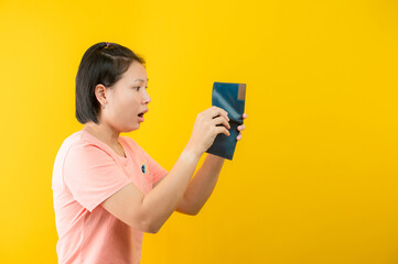 Portrait of a woman holding a wallet regretting that there is no money in her purse against a yellow background.concept saving.