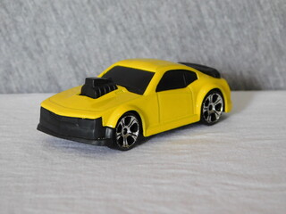 Fototapeta na wymiar Car miniature, sedan toy for kids withyellow paint and black tires with turbo engine.