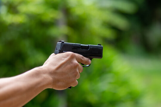 selective focus pistol in man's hand leaning forward in shooting range concept of violence Using guns in public areas, the rate of firearms.