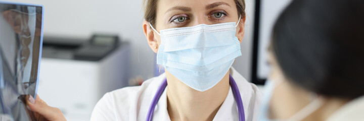 Doctor wearing protective medical mask shows patient X-ray