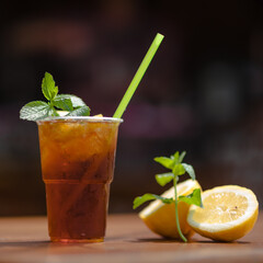 Iced tea in a plastic cup decorated with fresh mint leaves and lemon