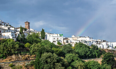 Fototapeta premium panorama of the town of Mairena of the Alpujarra with white houses, church tower, lots of vegetation and a rainbow