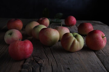 Fototapeta na wymiar textured apples in the garden on a dark background in a ray of light