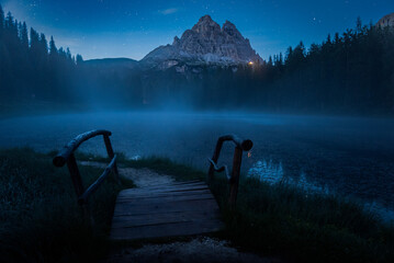 Fototapeta premium lago antorno di notte, con nebbia che si alza dal lago, e la luce del rifugio auronzo sotto le tre cime di lavaredo
