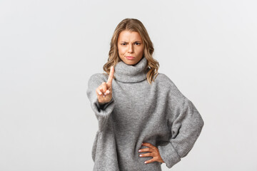 Image of serious and angry blond woman telling to stop, shaking finger disappointed, scolding...