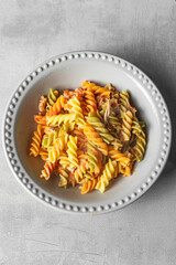 colored pasta in plate on rustic background