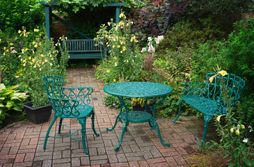 Beautiful cast iron table and chairs surrounded by garden with flowers. Beverley, UK.