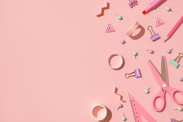 Above photo of scissors tape paper clips triangle pins pencil marker and spirals isolated on the pink backdrop with copyspace