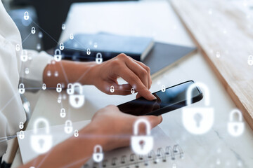 A woman programmer is browsing the Internet in smart phone to protect a cyber security from hacker attacks and save clients confidential data. Padlock Hologram icons over the typing hands. Formal wear