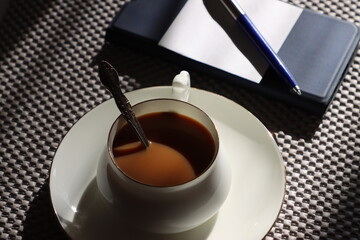 a cup of coffee, a smartphone, a pen and a piece of paper - always in the morning before work