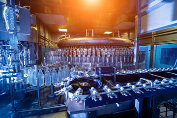 Automatic filling machine pours water into plastic PET bottles at modern beverage plant.