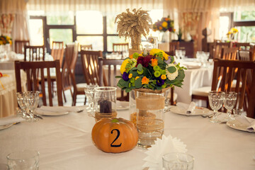 Obraz premium Festive floristry in autumn style with numbering of tables on pumpkins in banquet hall.