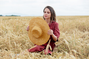 Naklejka na ściany i meble girl with straw hat on a yellow wheat field